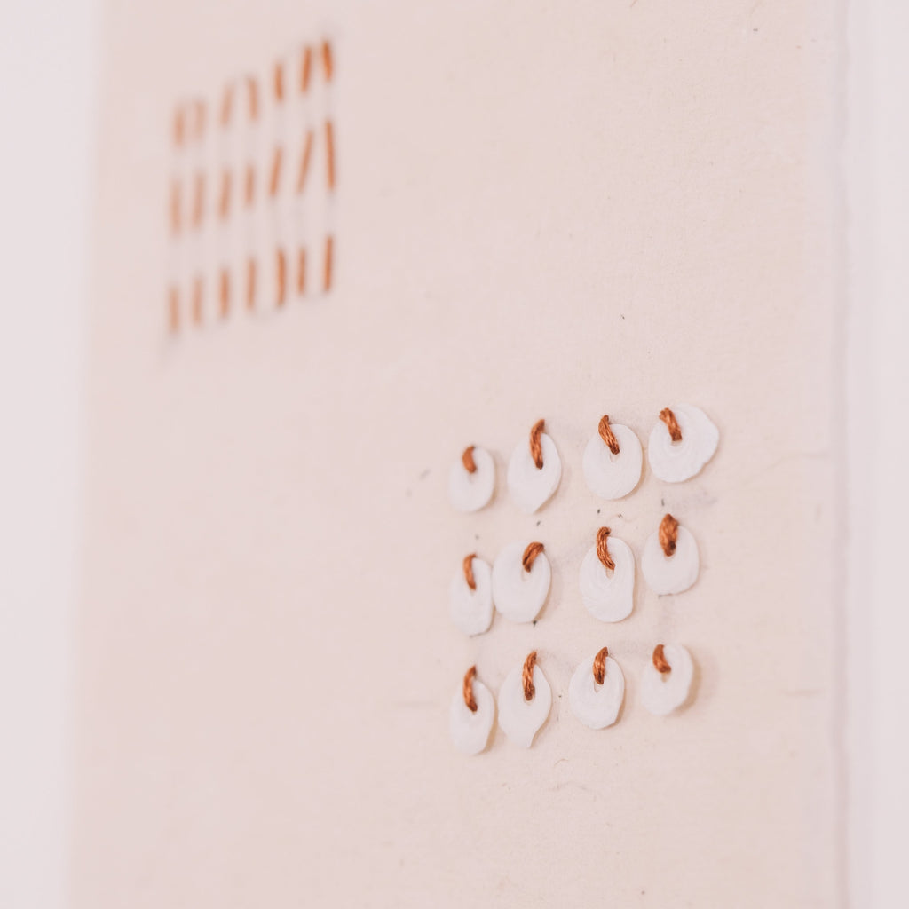 close up of thread and shell artwork 